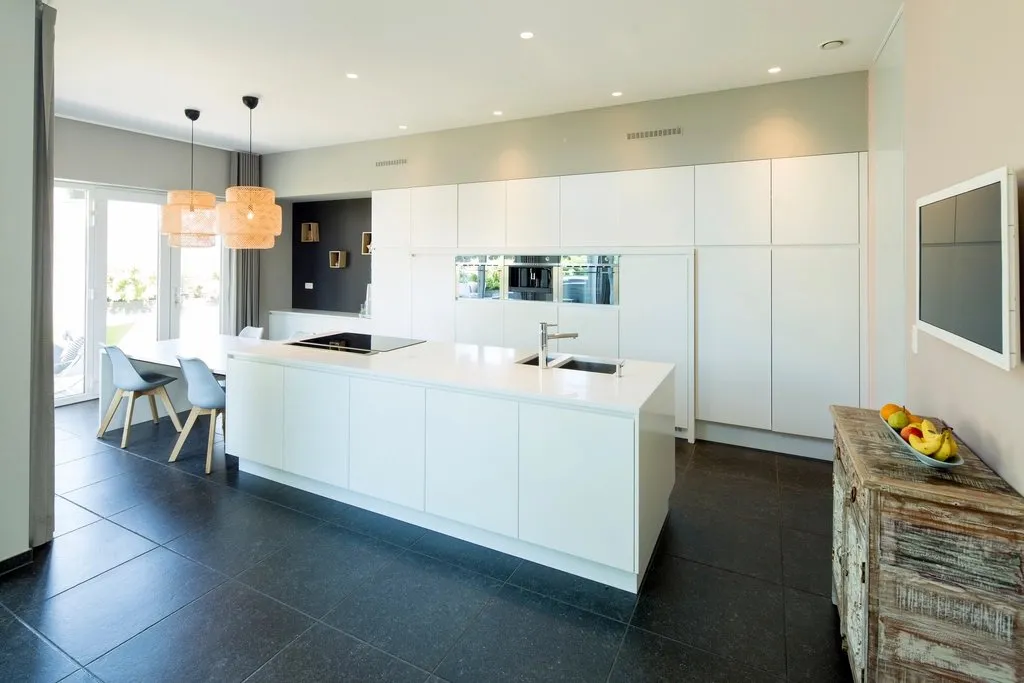 Cocina blanca reformada con isla y luz natural